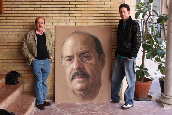 Professor D. Francisco Borras Cervera stands next to Ruben Belloso Adorno and his portrait at the Faculty of Fine Arts in Seville