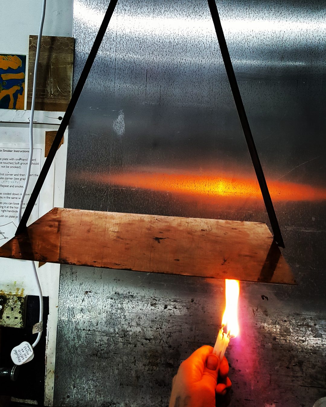 Melting rosin to a copper plate using a flame (photo taken at Spike Print Studio, Bristol)