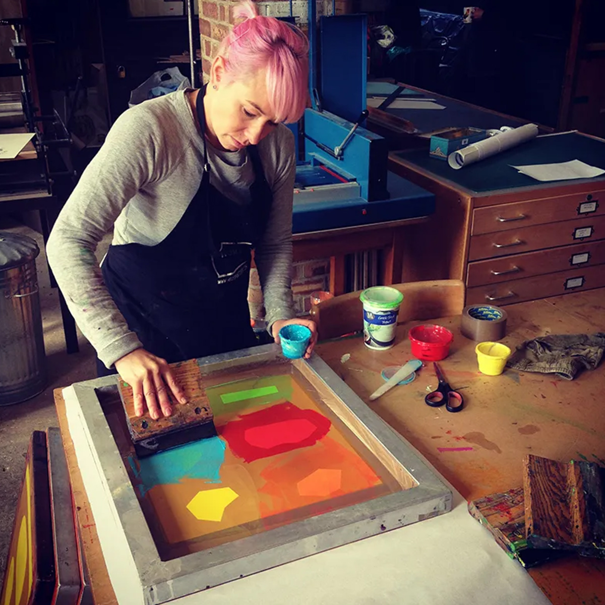 A printmaker doing printmaking in the studio using colourful inks