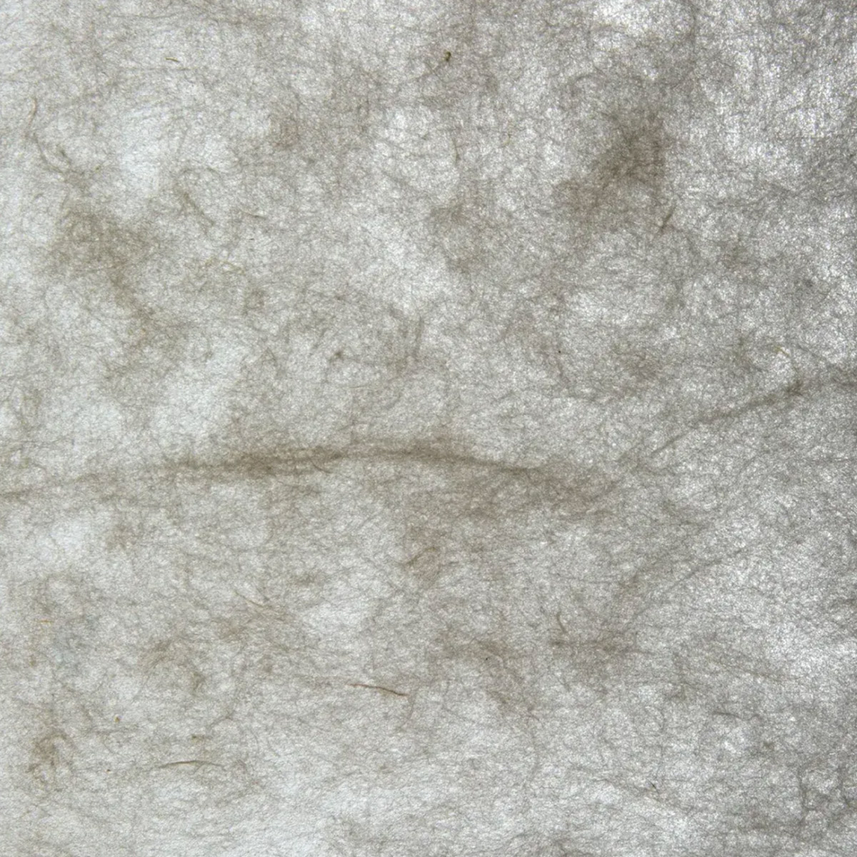 A close-up of a textured printmaking paper with light coming through